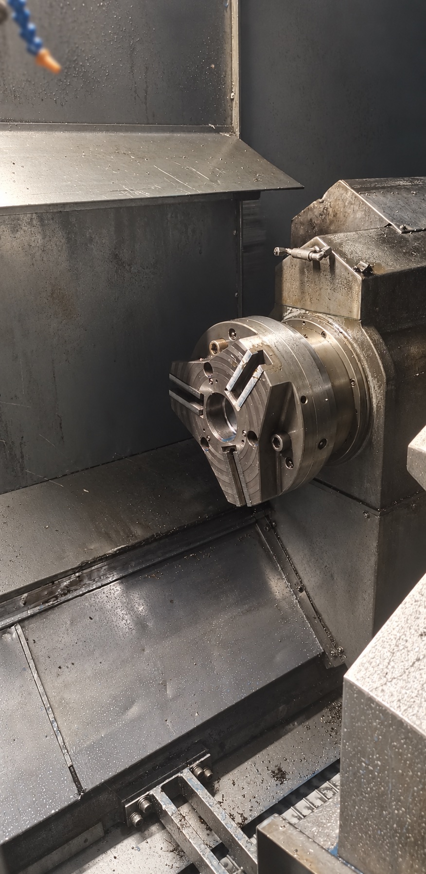 Large workholding chuck and jaws inside a CNC lathe enclosure